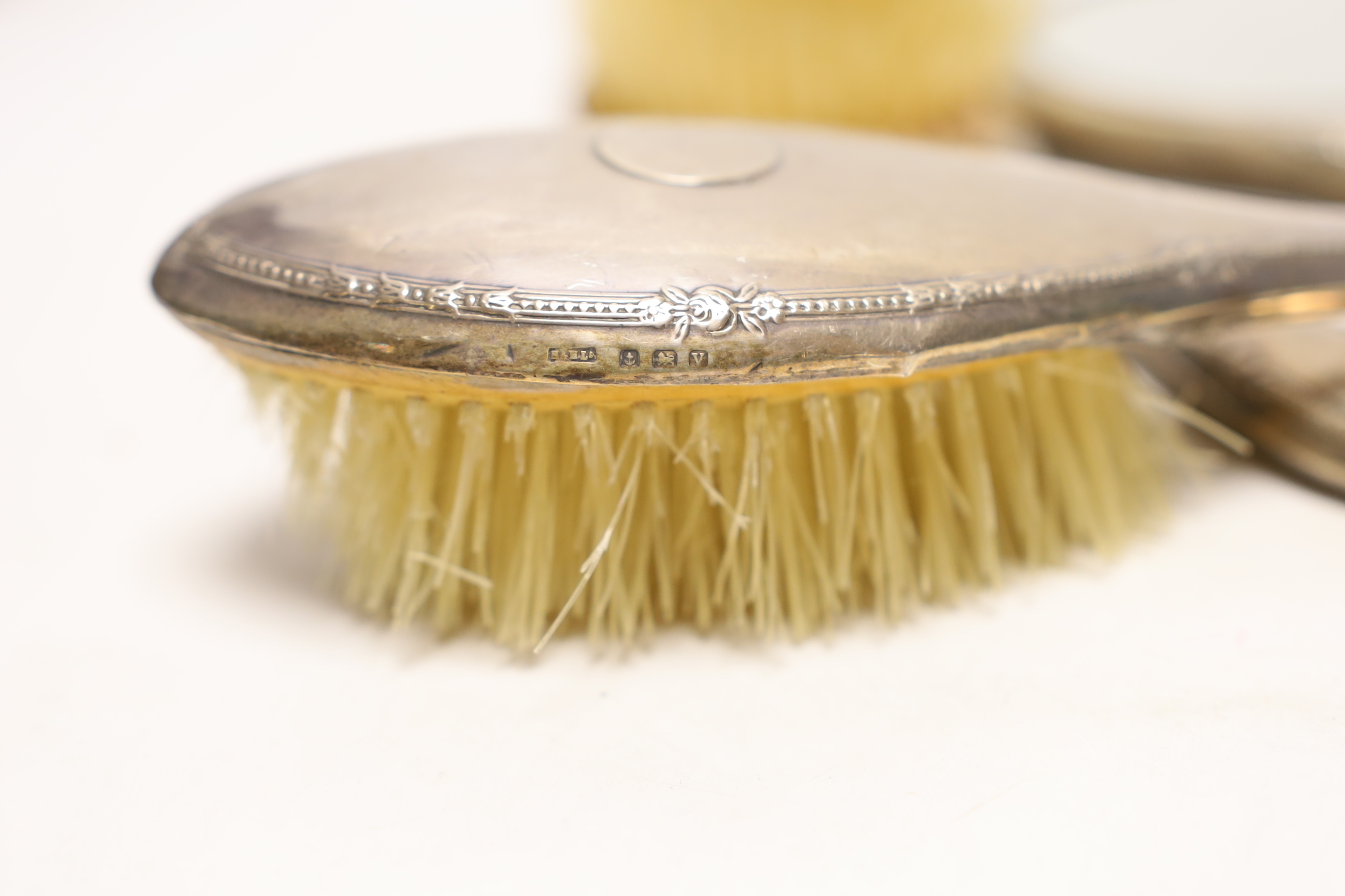 A pair of silver mounted hair brushes and a silver mounted hand mirror.